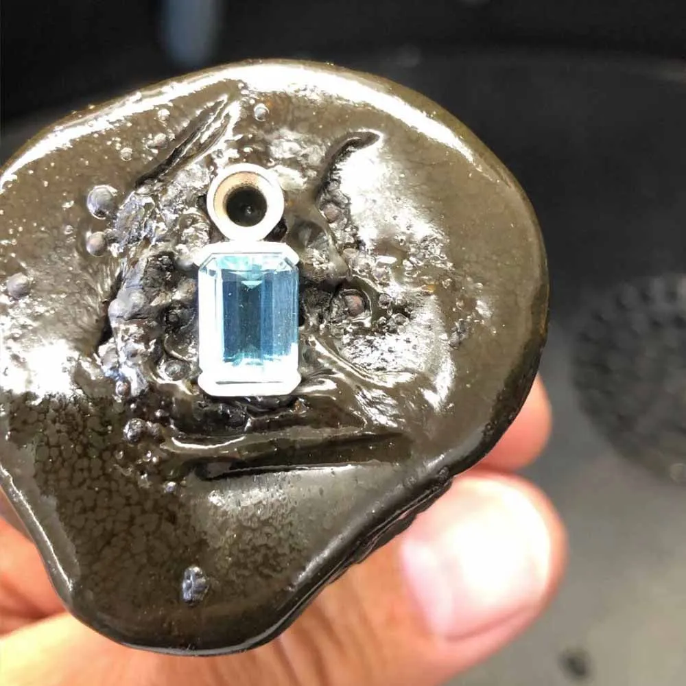 An aquamarine being set, held in setting wax