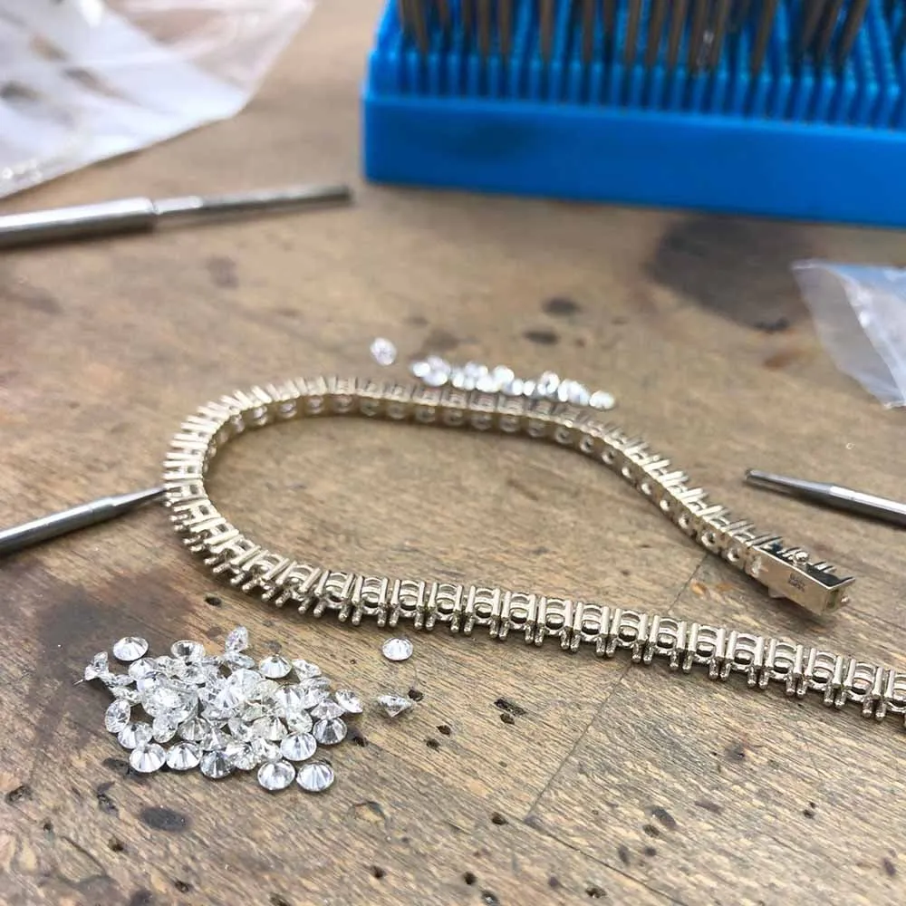 A diamond line bracelet on the bench with loose diamonds